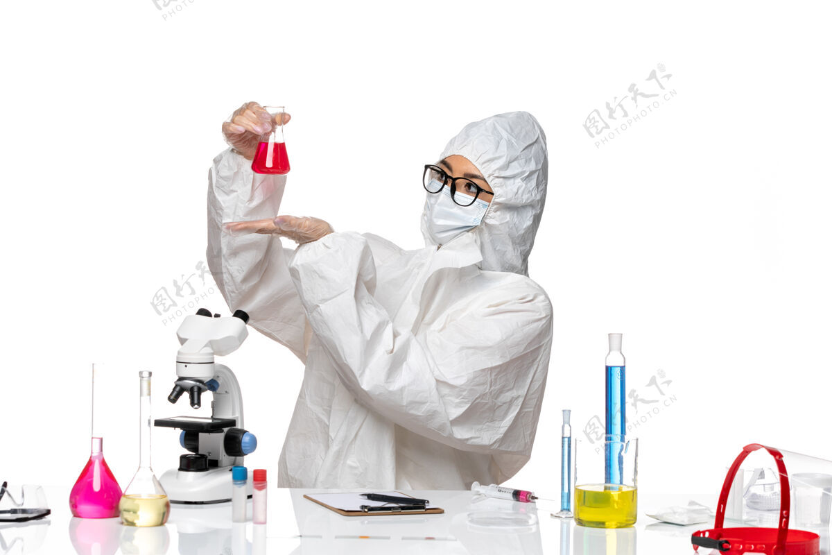 保护前视图穿着特殊防护服的女化学家拿着白色背景上的红色溶液-化学病毒实验室实验室专业病毒