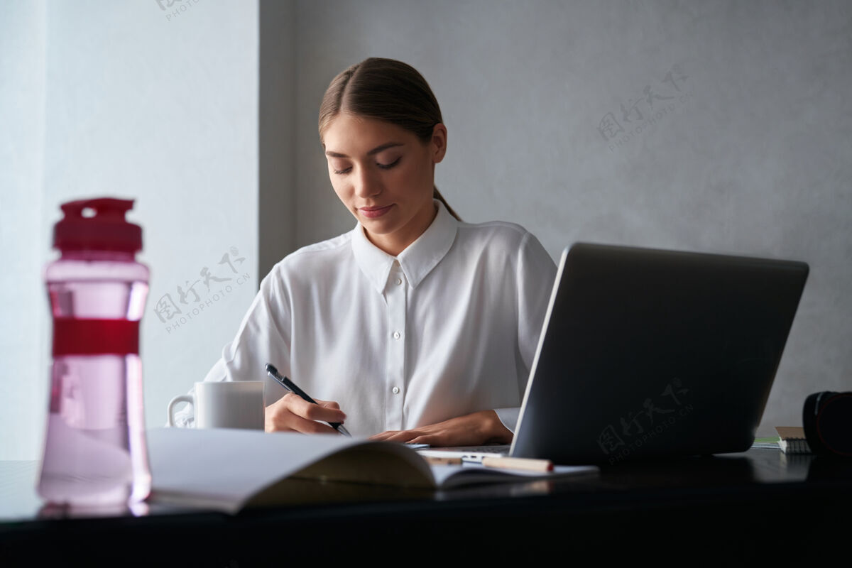 工作专心工作的女人在家里用笔记本电脑坐着笔记本电脑年轻