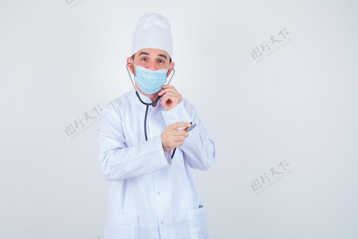 虽然帅哥拿着听诊器的耳塞在耳朵里 仿佛他穿着白色的医学实验服 戴着口罩 看上去很开心 正对着前方看衬衫快乐听诊器