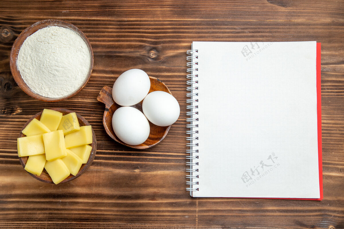 面粉俯视整个生鸡蛋与面粉和奶酪在棕色桌上鸡蛋面团面粉粉尘产品顶部生的鸡肉
