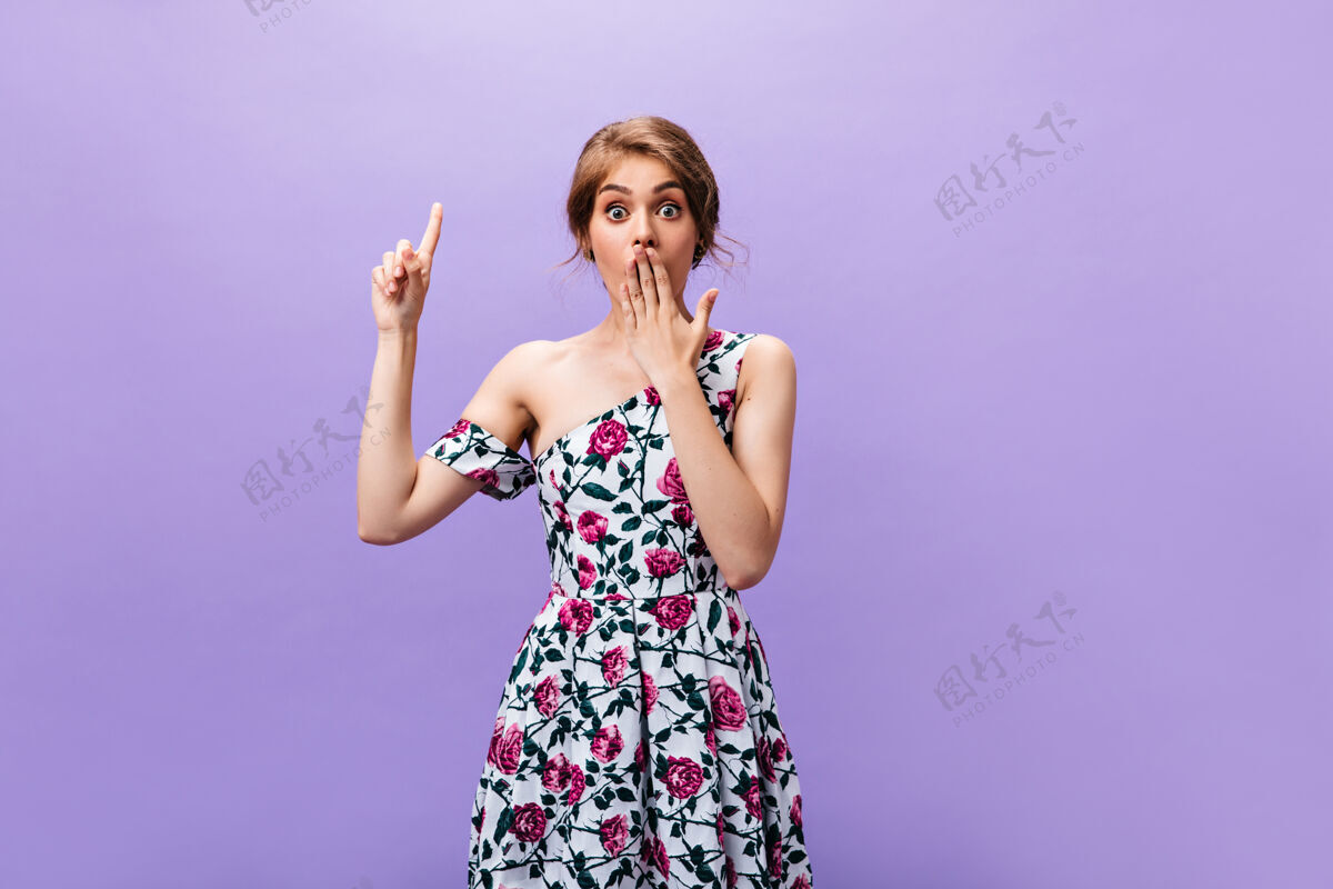 表情惊艳的穿着裙子的女人指着孤立的背景漂亮时髦的女孩穿着五颜六色鲜艳的夏装有很酷的想法女孩年轻紫色