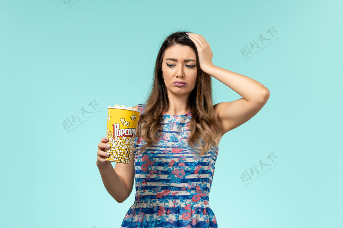电影正面图年轻女性拿着爆米花包在蓝色的表面上吃漂亮电影剧院