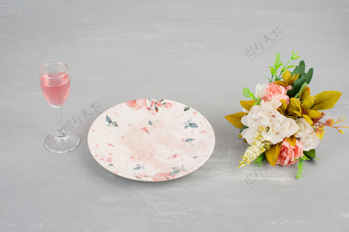单身鲜花 盘子和一杯玫瑰红酒放在灰色的表面上花叶子盘子