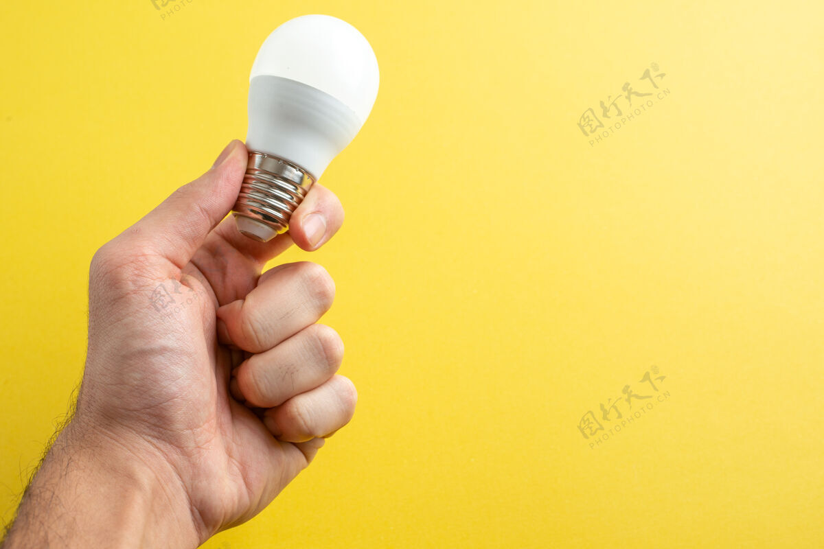灯泡正面图白色灯泡放在男性手上黄色背景色光照电灯房人背景灯泡手