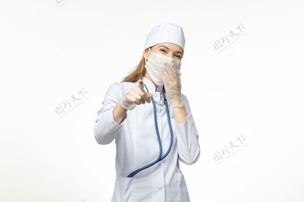 冠状病毒正面图：穿着白色医疗服 戴着口罩的女医生 可以抵御冠状病毒在白墙上笑的疾病——冠状病毒大流行肖像视野人