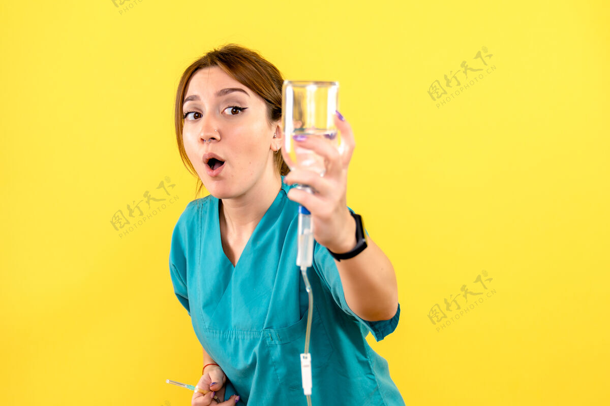 人黄色墙上的女兽医拿着滴管的正视图抱健康女兽医