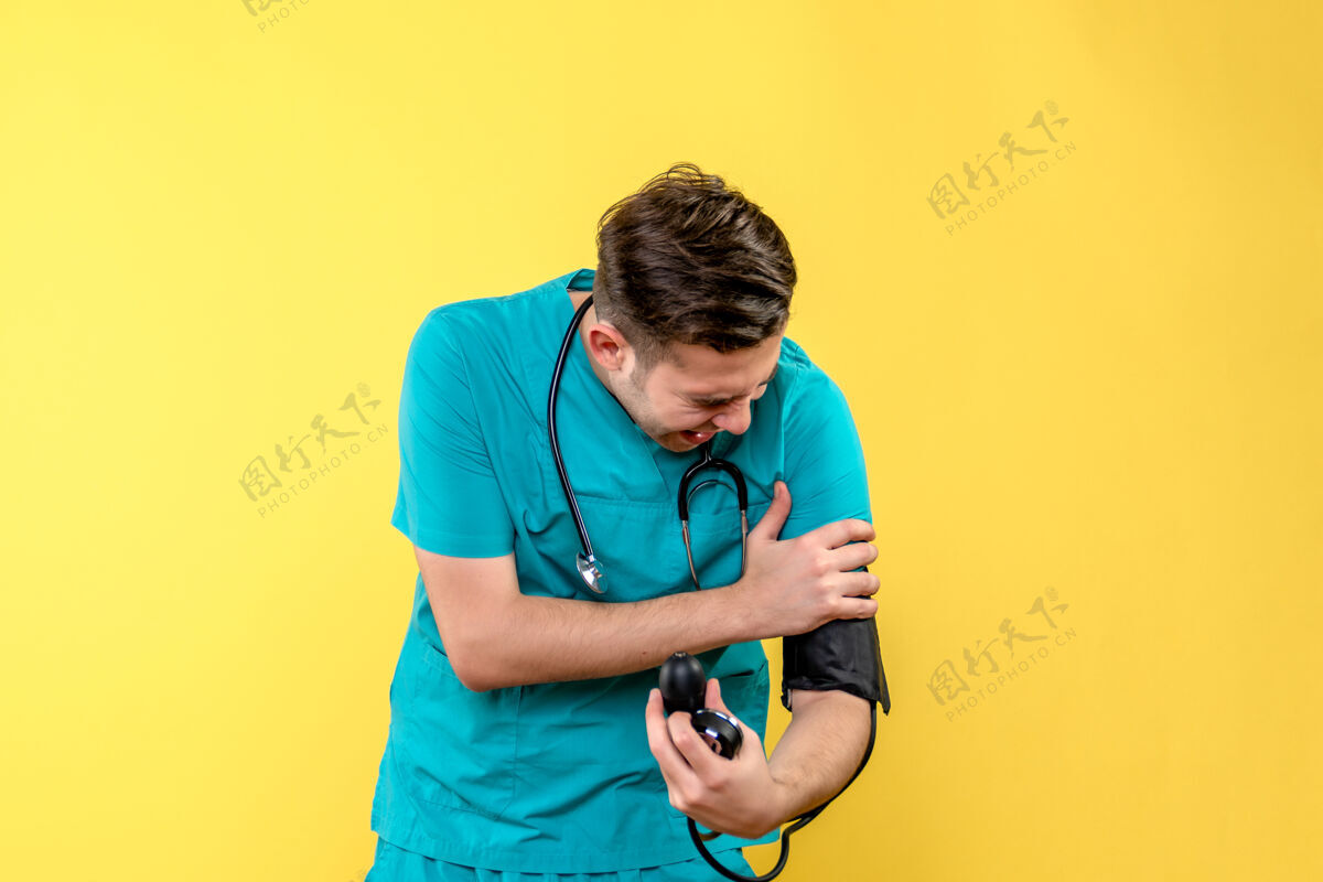 医生男医生在黄色墙壁上测量压力的正视图仪器设备压力