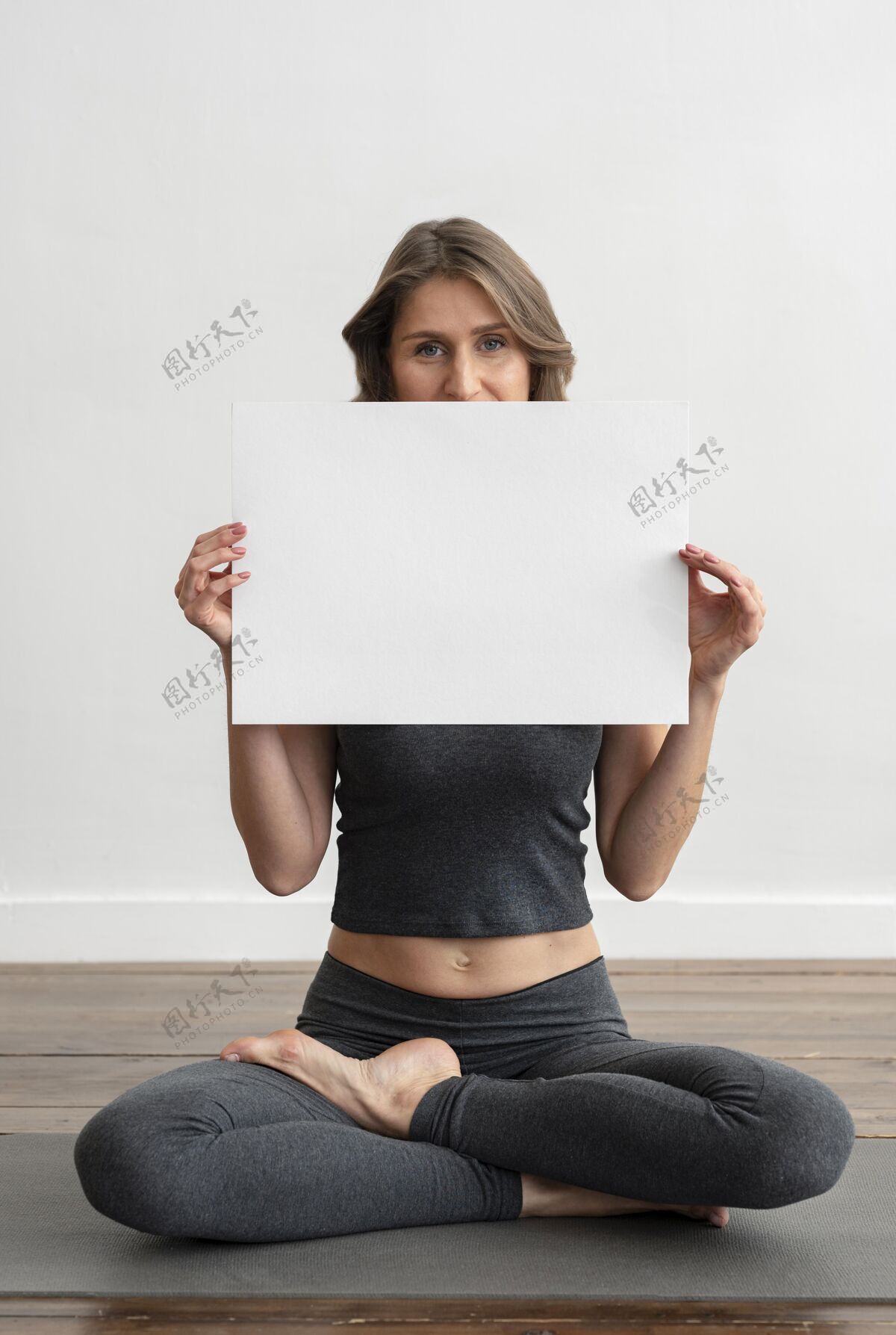 瑜伽前视图的妇女持有空白标语牌 而做瑜伽休闲垫子反省