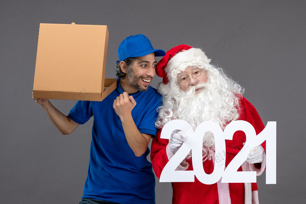 圣诞圣诞老人的正面图 灰色的墙上有男信使拿着购物袋和食品盒快乐老人食物
