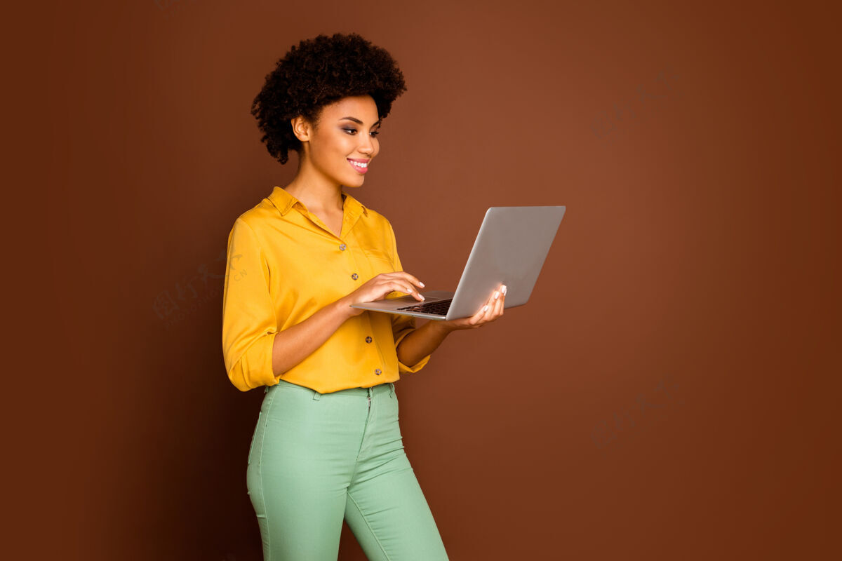 时尚资料照片美丽的深色皮肤波浪女士拿着笔记本手搜索公司信息写电子邮件穿黄色衬衫绿色裤子孤立的棕色多民族混血儿个人资料