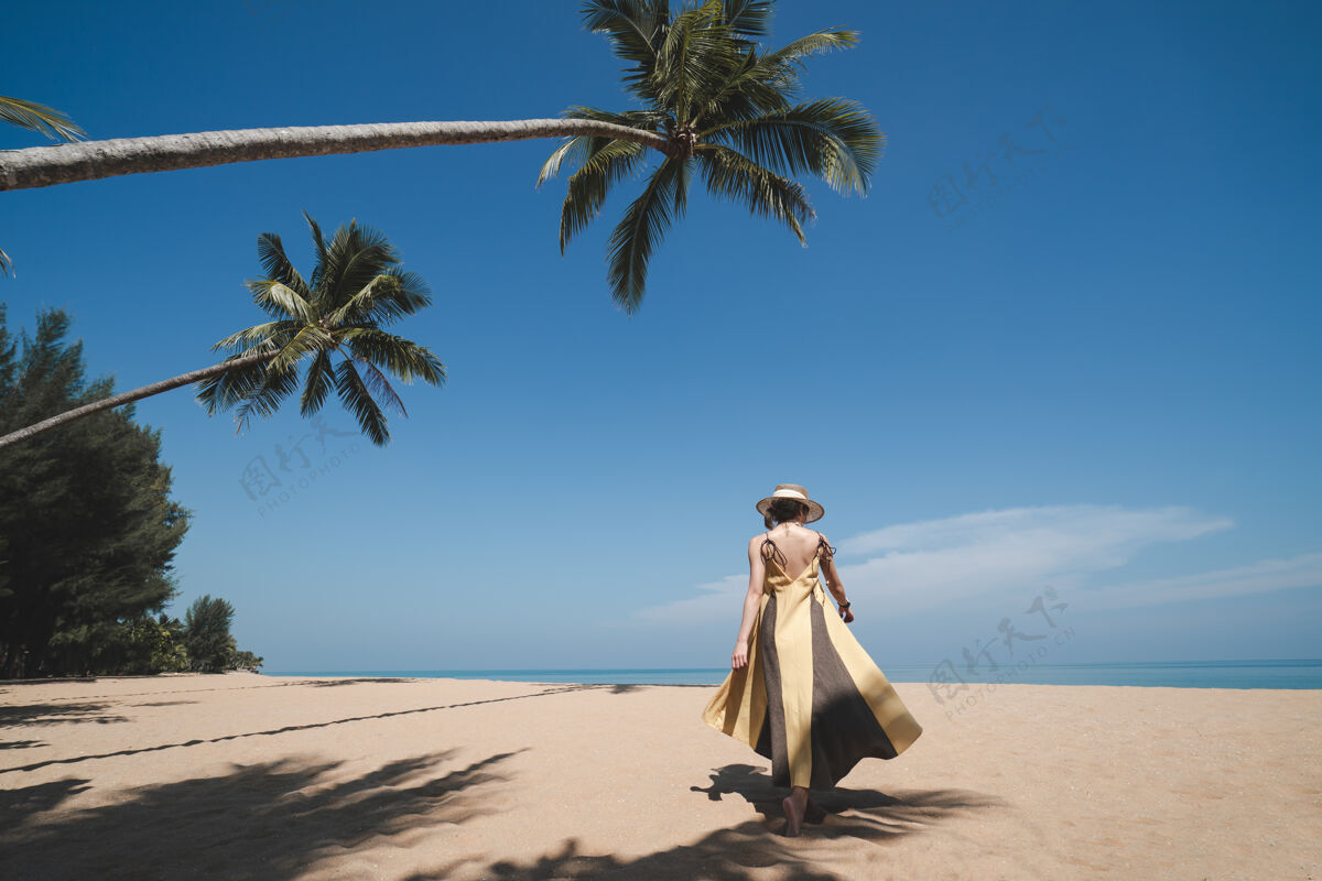 海边走在椰子树下的女人 在沙滩上 天空湛蓝温暖海滩天堂