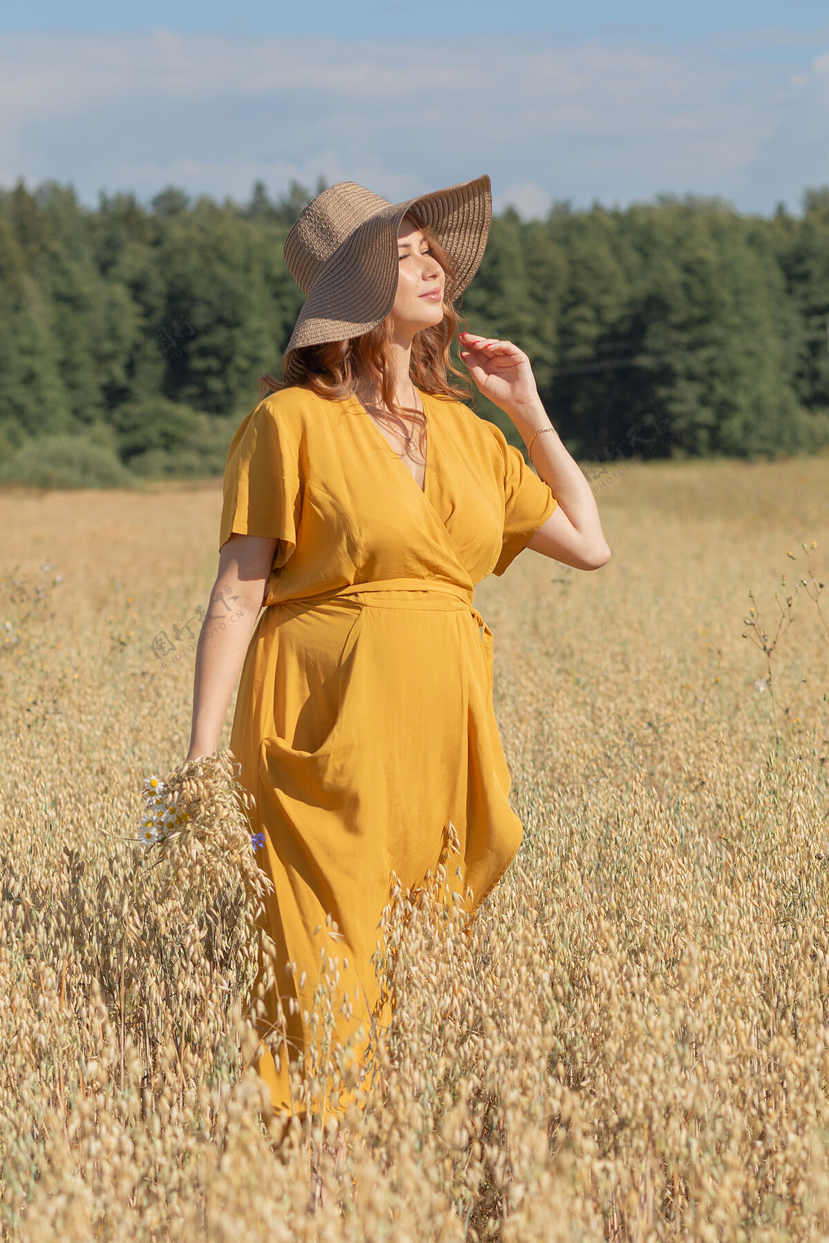 黄色在一个阳光明媚的夏日 一位年轻漂亮的孕妇穿着黄色的裙子 戴着黄色的帽子 走过一片麦田欢呼婴儿肥料