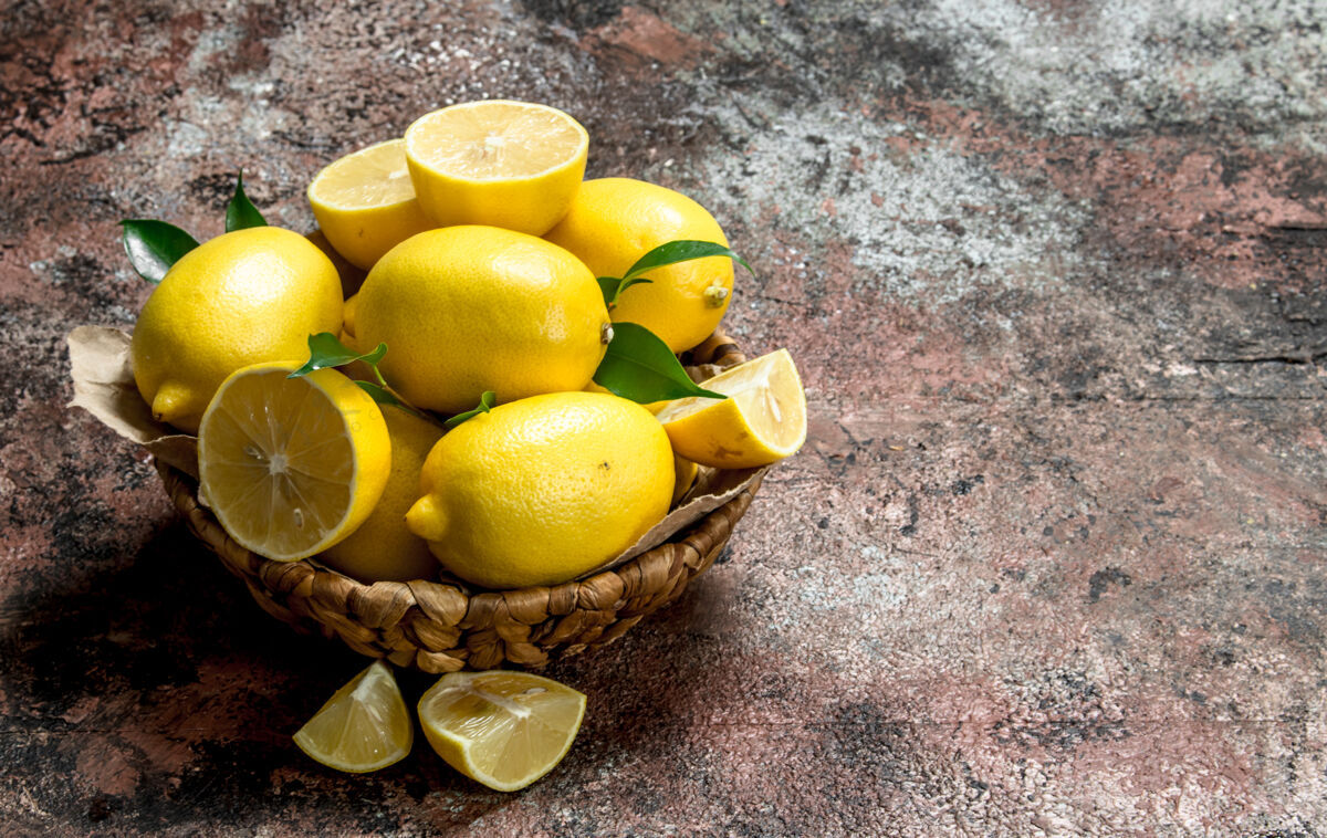 多汁柠檬和树叶在篮子里放在乡村的桌子上黄色收获篮子