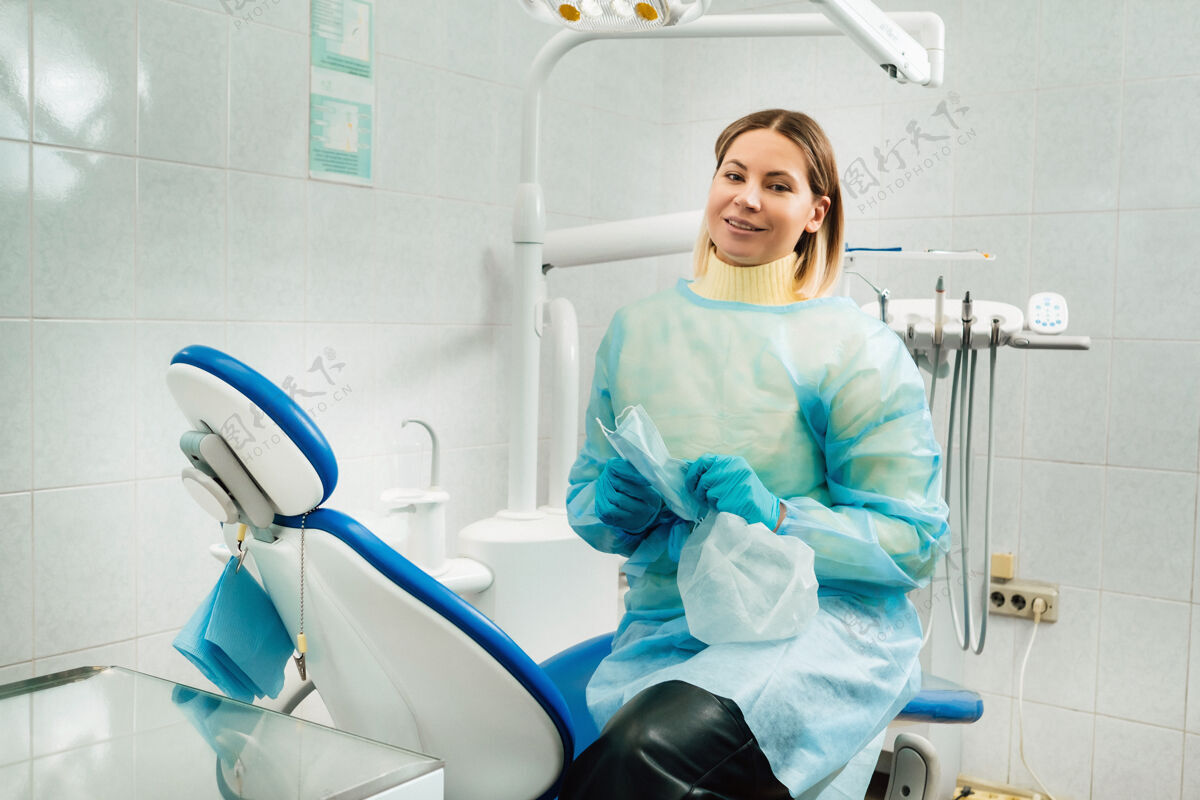 实习一位戴着医用口罩和橡胶手套的女牙医坐在她的办公室里预防手套医疗