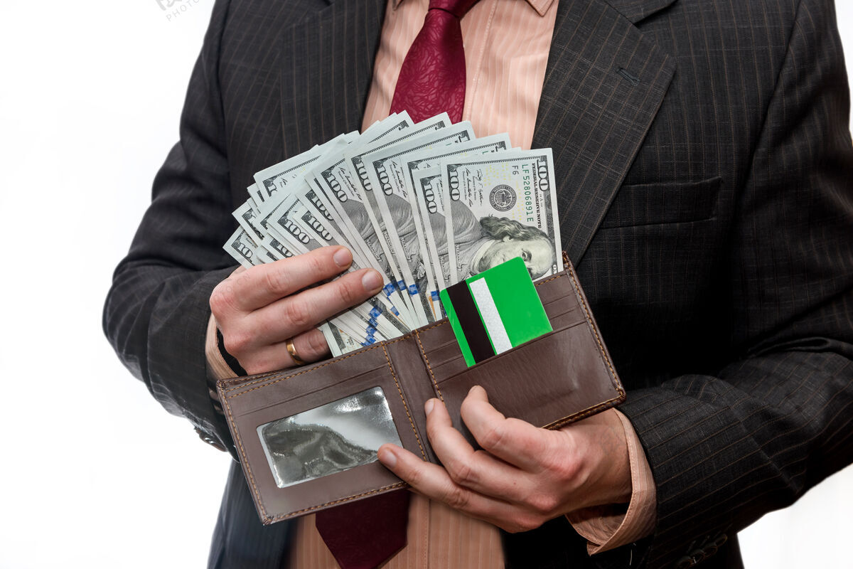 纸西装革履的男人拿着钱包 里面有美元钞票和信用卡钱人借方
