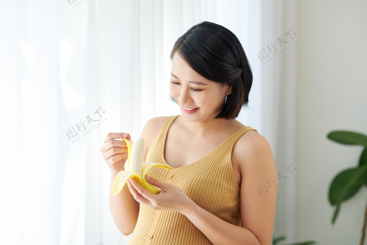 立场孕妇在厨房做健康果汁吃香蕉水果女性新鲜