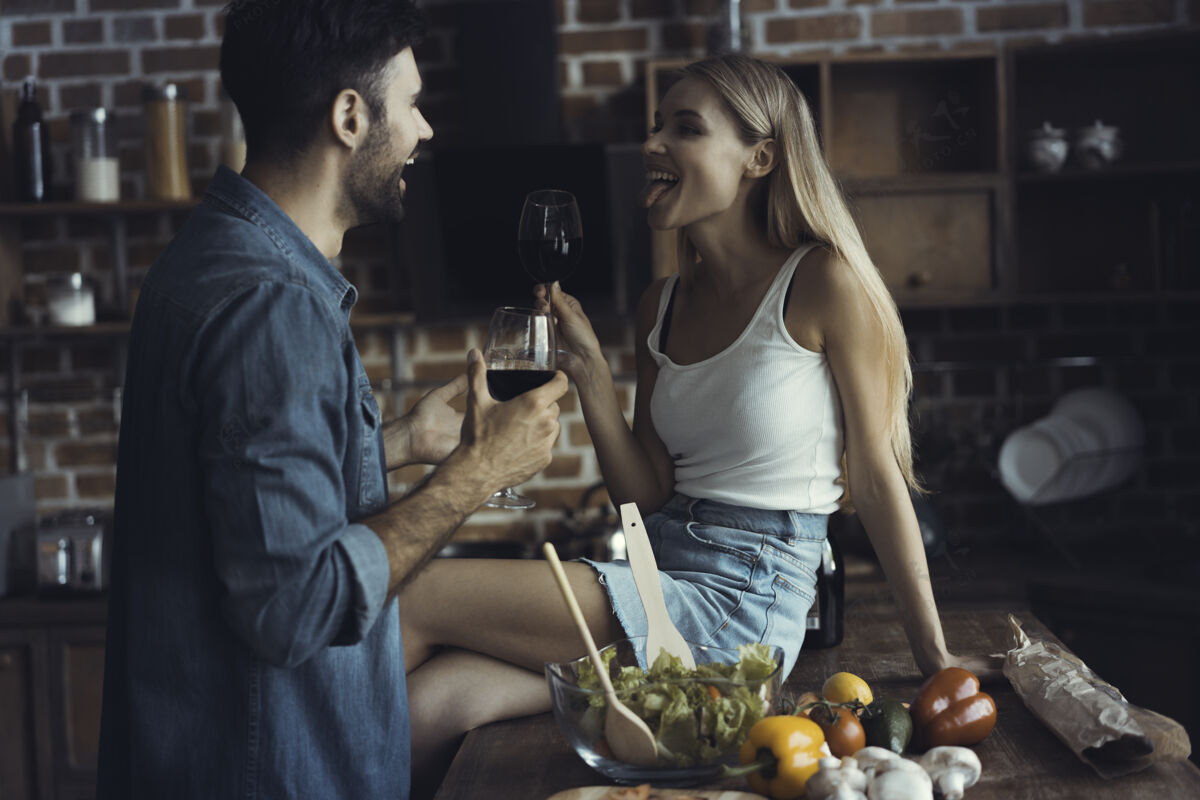 食谱美丽的年轻夫妇在家里的厨房边喝酒边微笑吃饮食婚礼