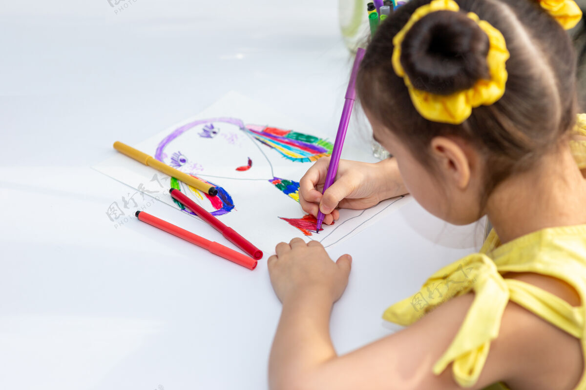年轻可爱的黑发女孩穿着黄色的裙子 画着彩色的记号小幼儿园色彩