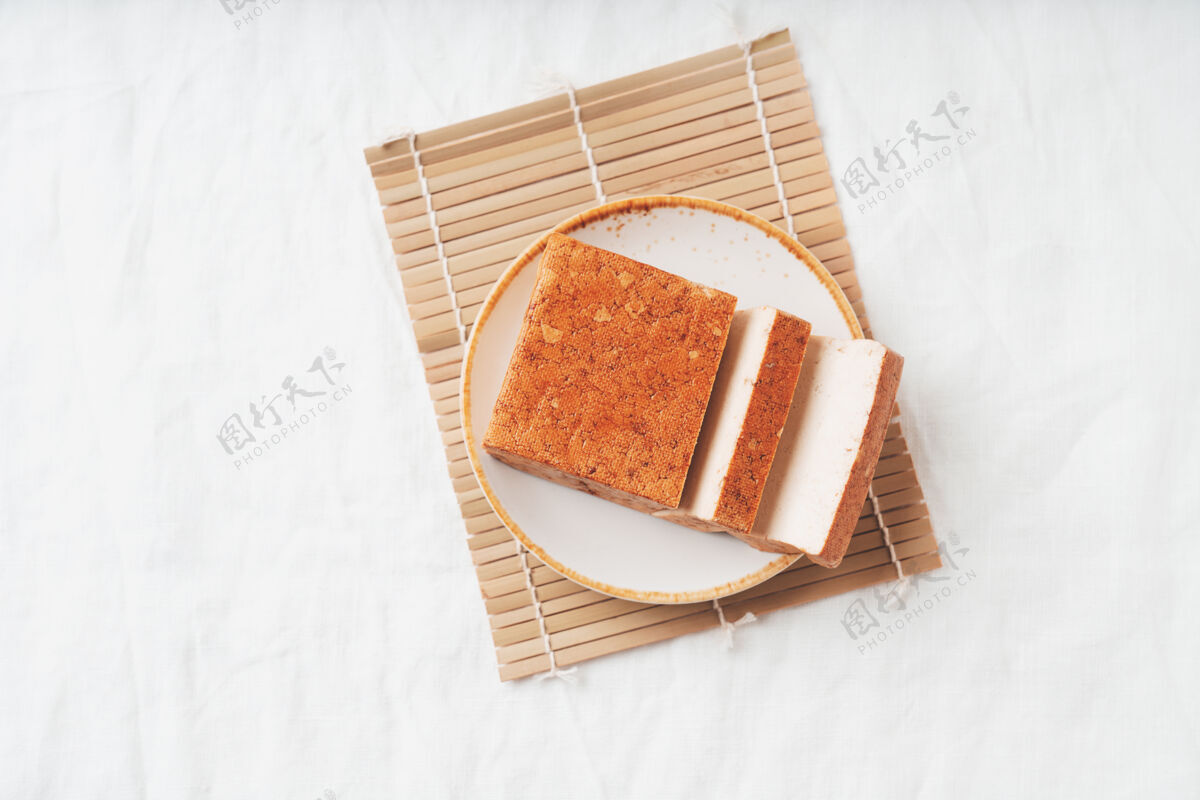 菜肴一块有机熟透的豆腐奶酪 放在白色盘子里 放在竹席上平铺顶视图素食小吃概念营养特写食物