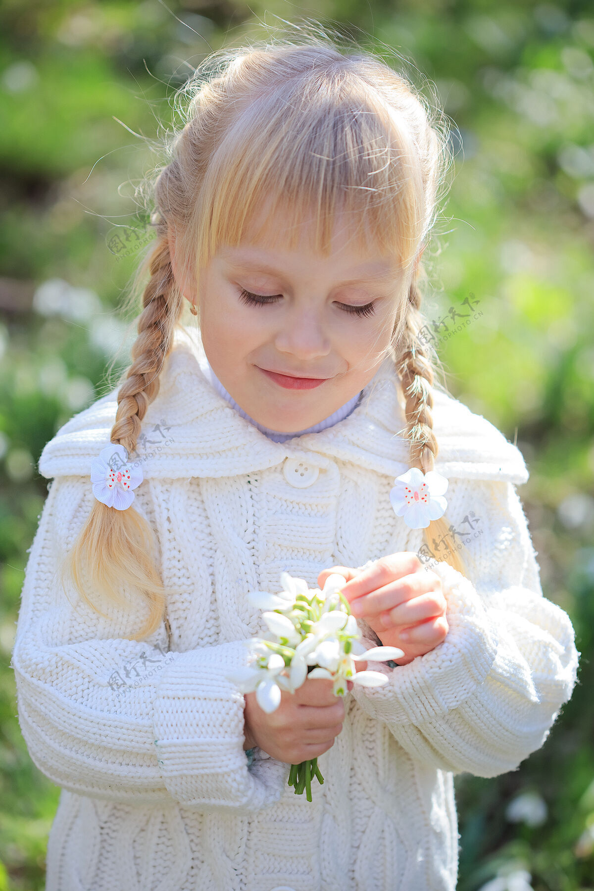 玩耍可爱的小女孩正在考虑一束新鲜的雪花莲春天穿白衣服的小女孩在森林里散步年轻欢呼美丽