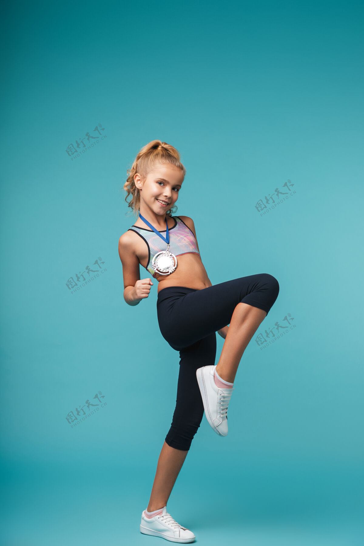 小一个可爱的小女孩拿着奖牌在蓝色的墙上摆出获奖者的姿势高加索表情锻炼