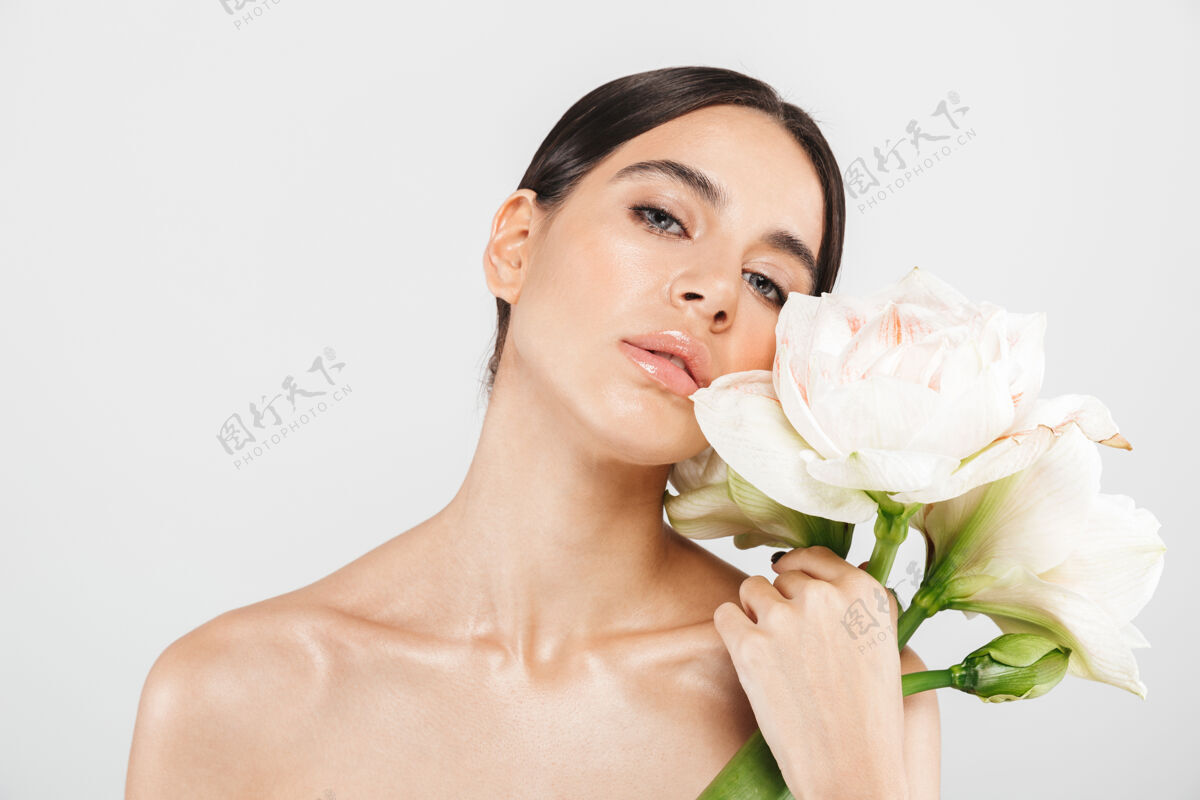 花美丽的肖像一个迷人的感官健康的女人站在隔离的白色墙壁 摆出一朵花完美年轻温柔