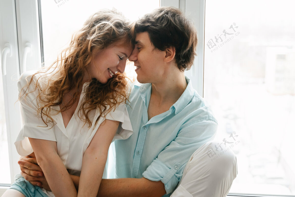 一起情人节快乐的女人和男人在家的窗户边接吻妻子年轻女人