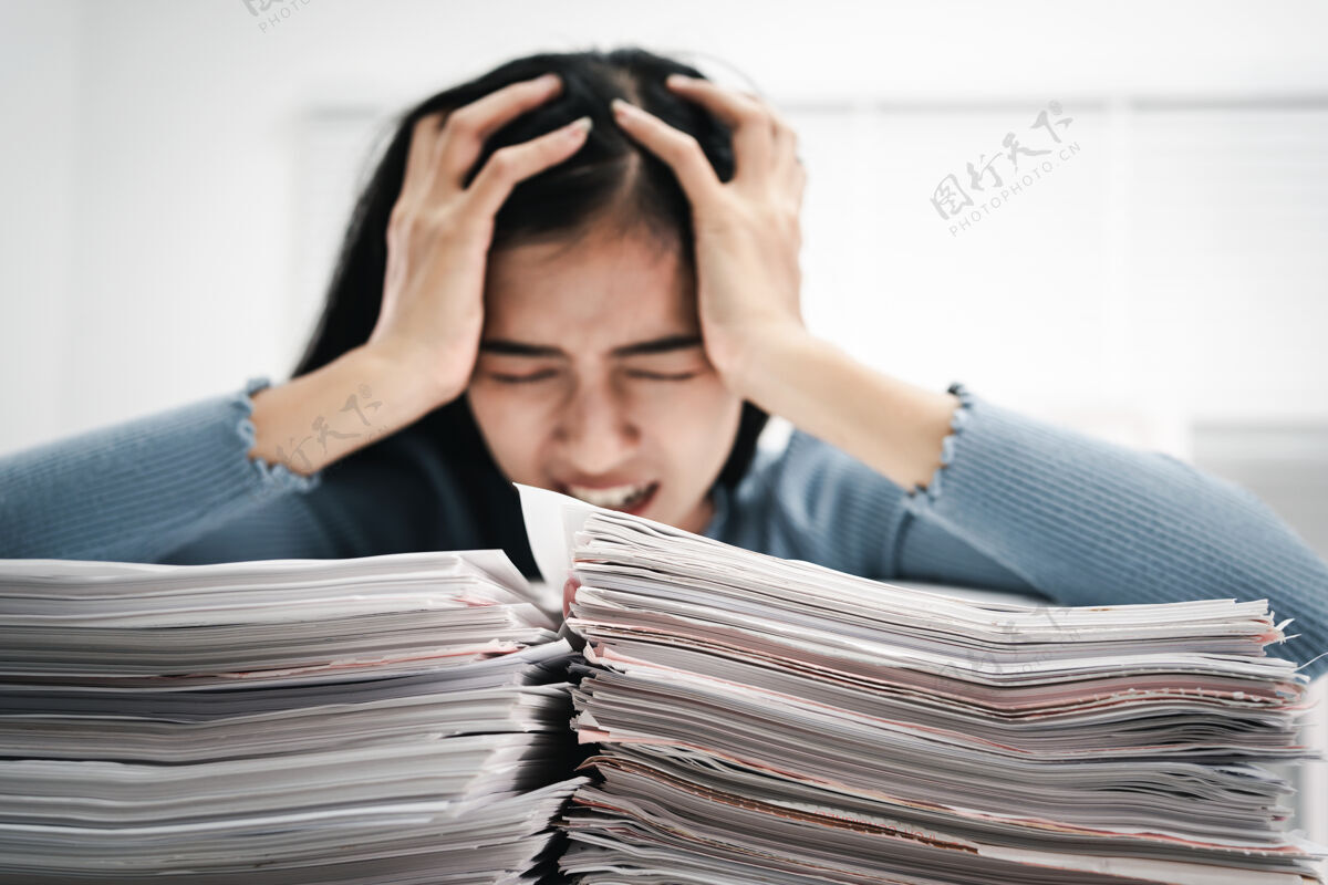 女人女人工作压力大幽默忙着把成堆的文件放在桌子上忙碌头痛员工