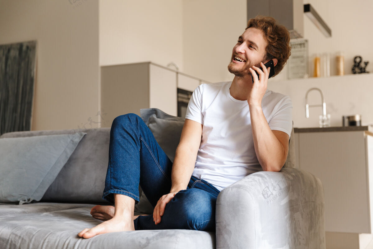 手机一个留着胡子的帅哥坐在家里的沙发上用手机聊天帅气休闲白种人