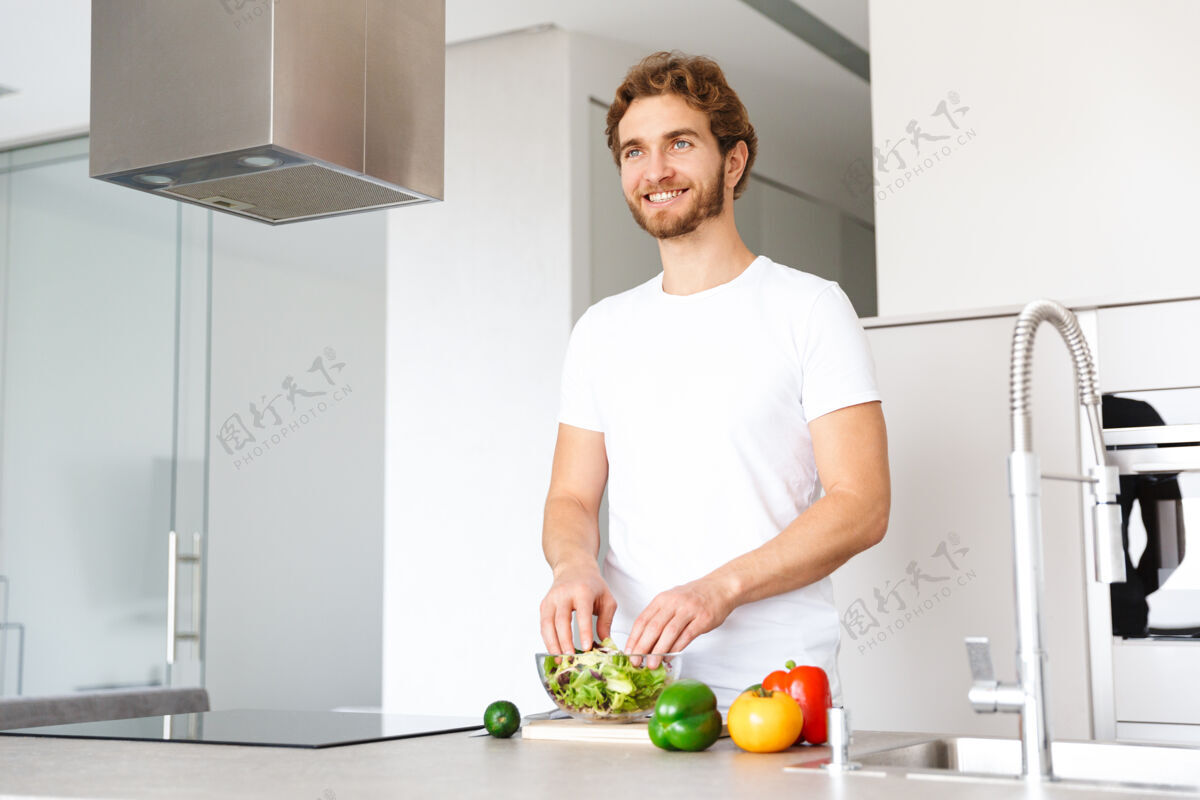 文学一个英俊的年轻人在厨房的照片在家做饭蔬菜做沙拉休闲白种人烹饪