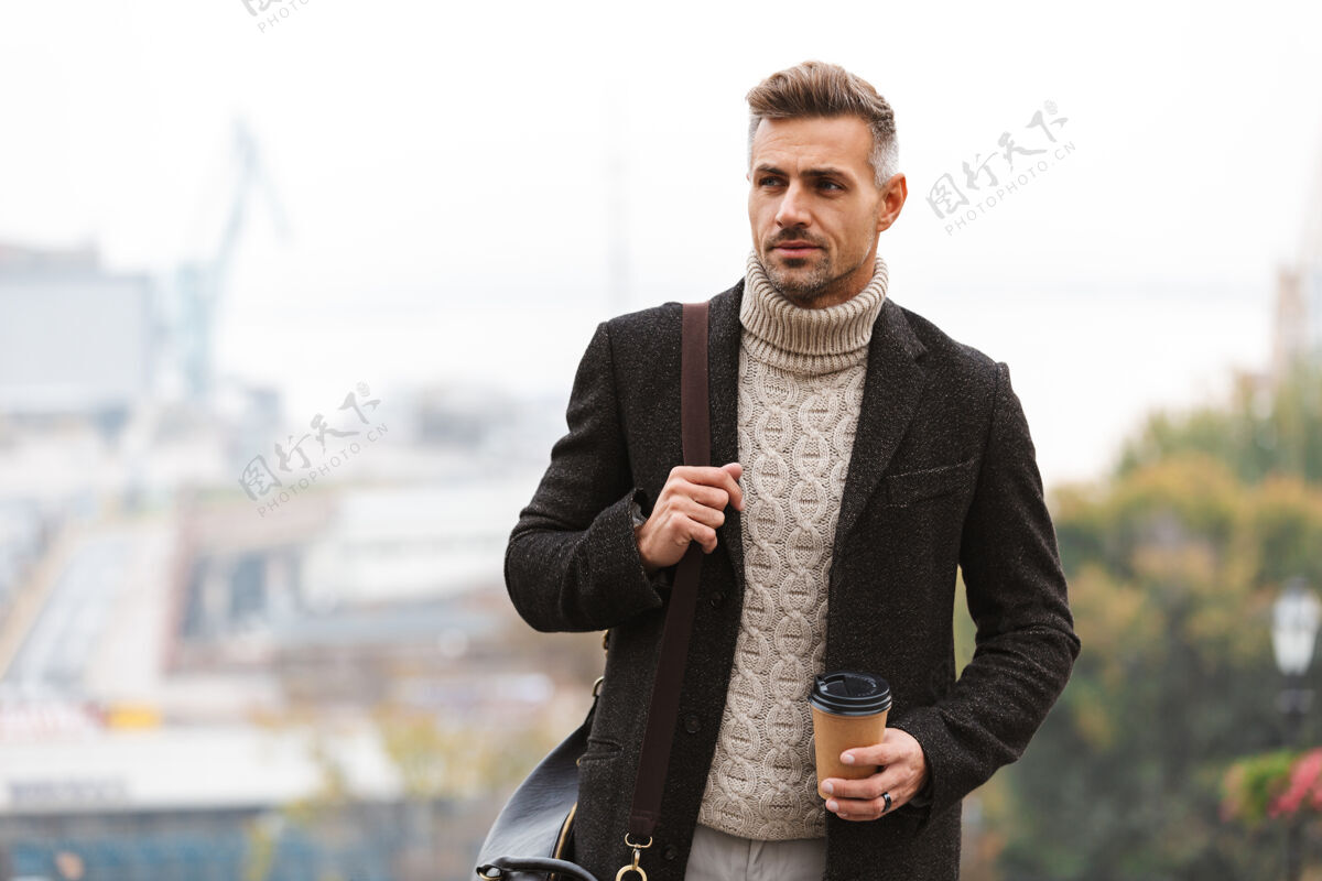 散步照片中 30多岁的欧洲成年男子身穿夹克 手里拿着外卖咖啡 一边走在城市街道上外卖成人咖啡