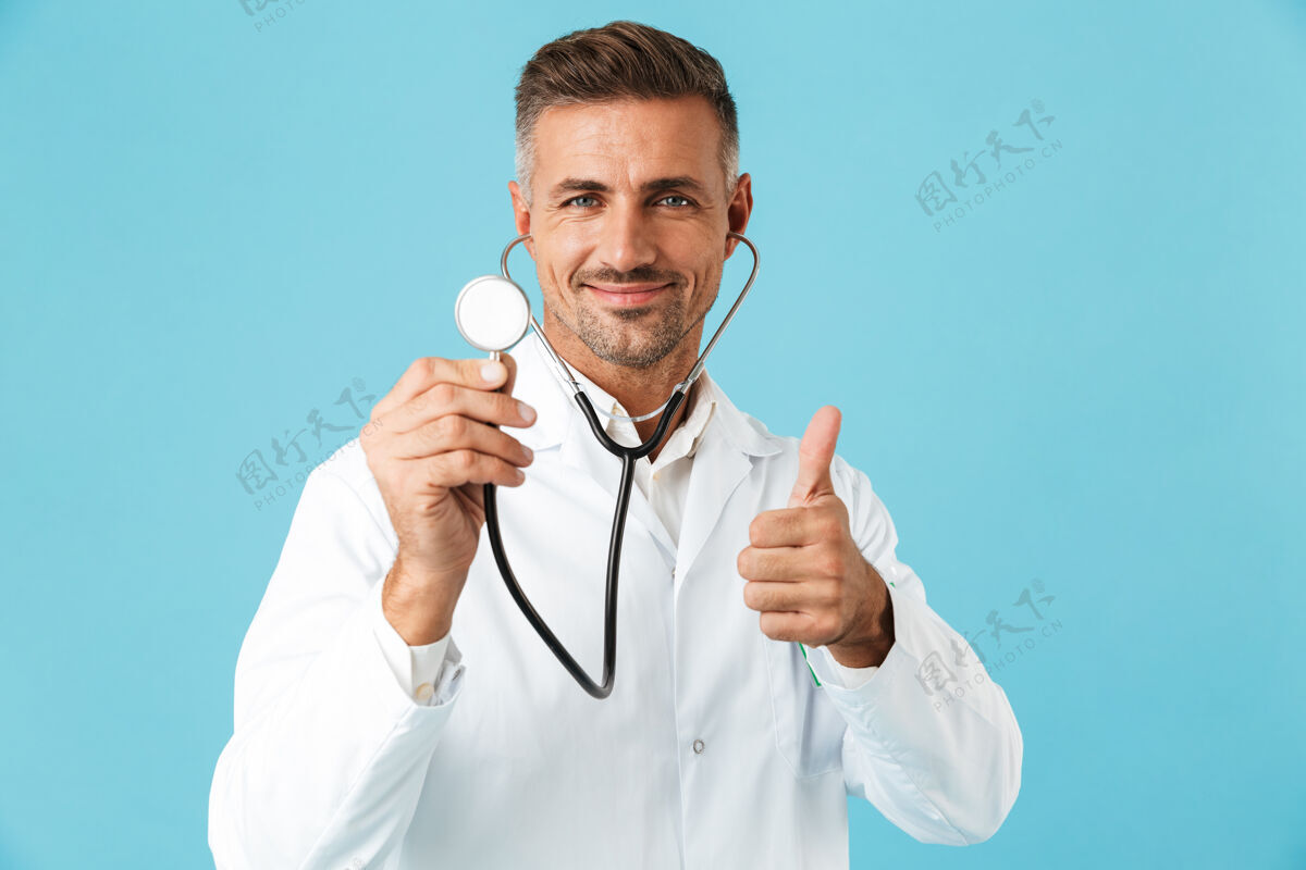 诊所中年医学专家的画像 身穿白大褂 手持听诊器 孤立地站在蓝色的墙上救护车制服白种人