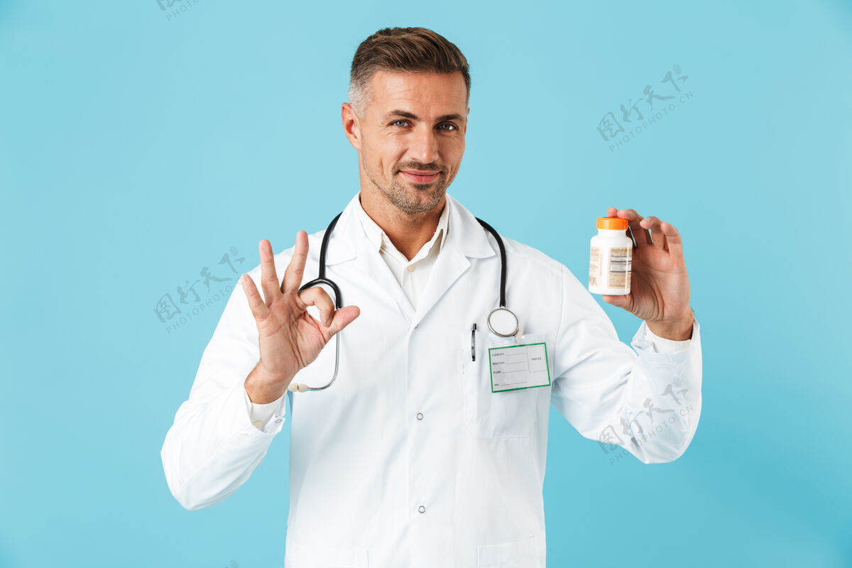 救护车年轻的医学专家穿着白大褂 手里拿着一罐药 孤零零地站在蓝色的墙上治疗成人诊所