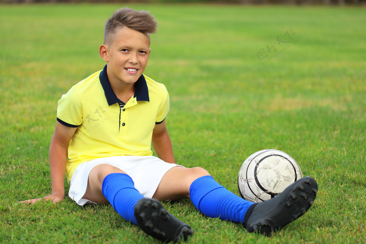 游戏穿着黄色t恤和蓝色gntra的帅哥足球运动员坐在足球场上足球运动员欧洲