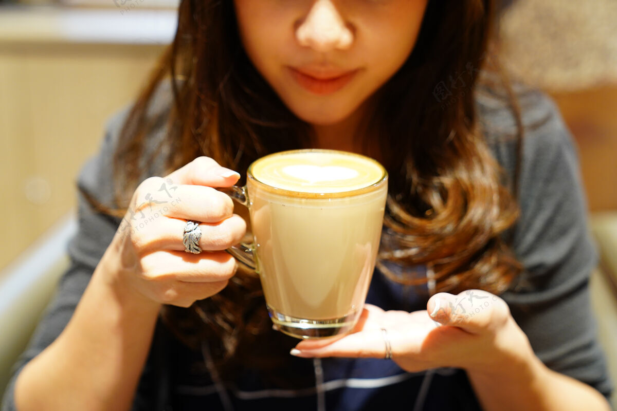 亚洲热拿铁咖啡在亚洲女孩手里 贴好就可以喝了早晨情感茶