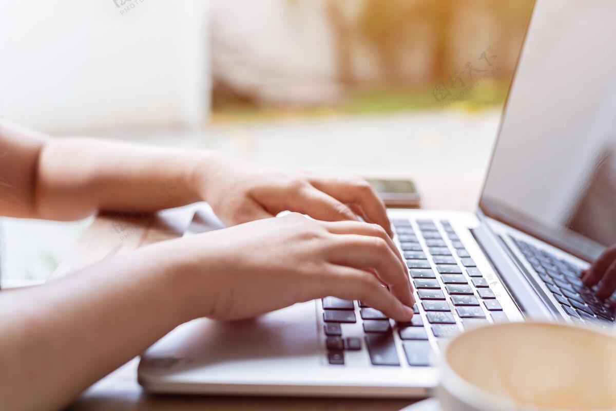 女孩特写自由职业者商务女性休闲工作用笔记本电脑咖啡杯和智能手机在咖啡店喜欢的背景工作场所工作休闲