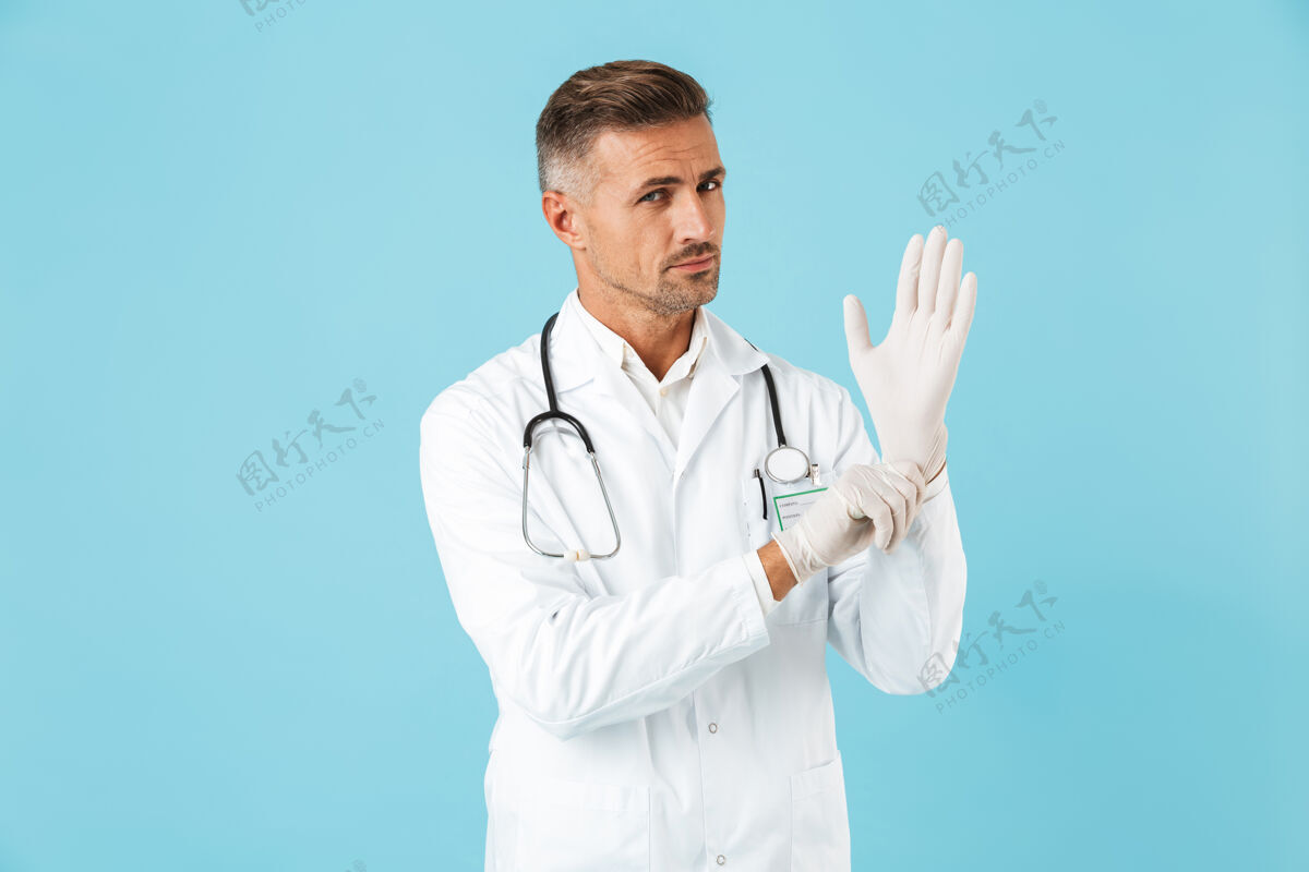 医生一个英俊的成熟男子医生在蓝色的墙上摆出孤立的姿势工人医疗从业者