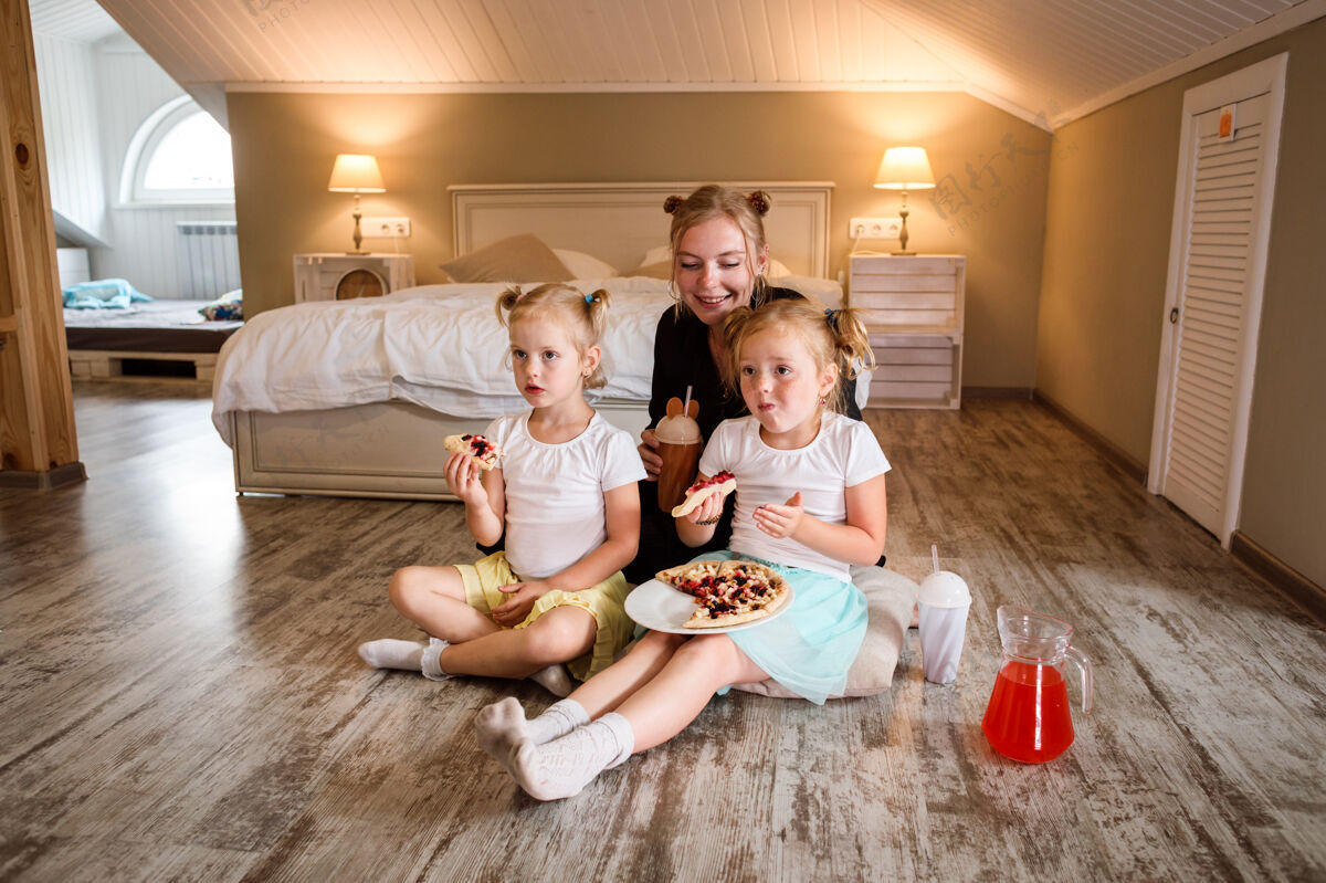 女儿妈妈和她的两个女儿看电视 吃比萨饼 喝果汁饮料电影房子