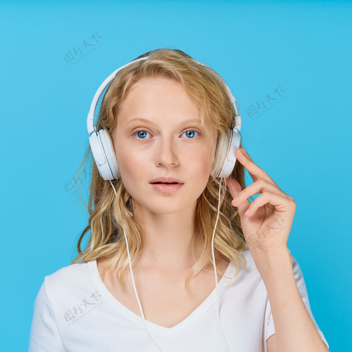 女孩特写肖像的年轻女子通过耳机听音乐的颜色明亮的蓝色调女人年轻听
