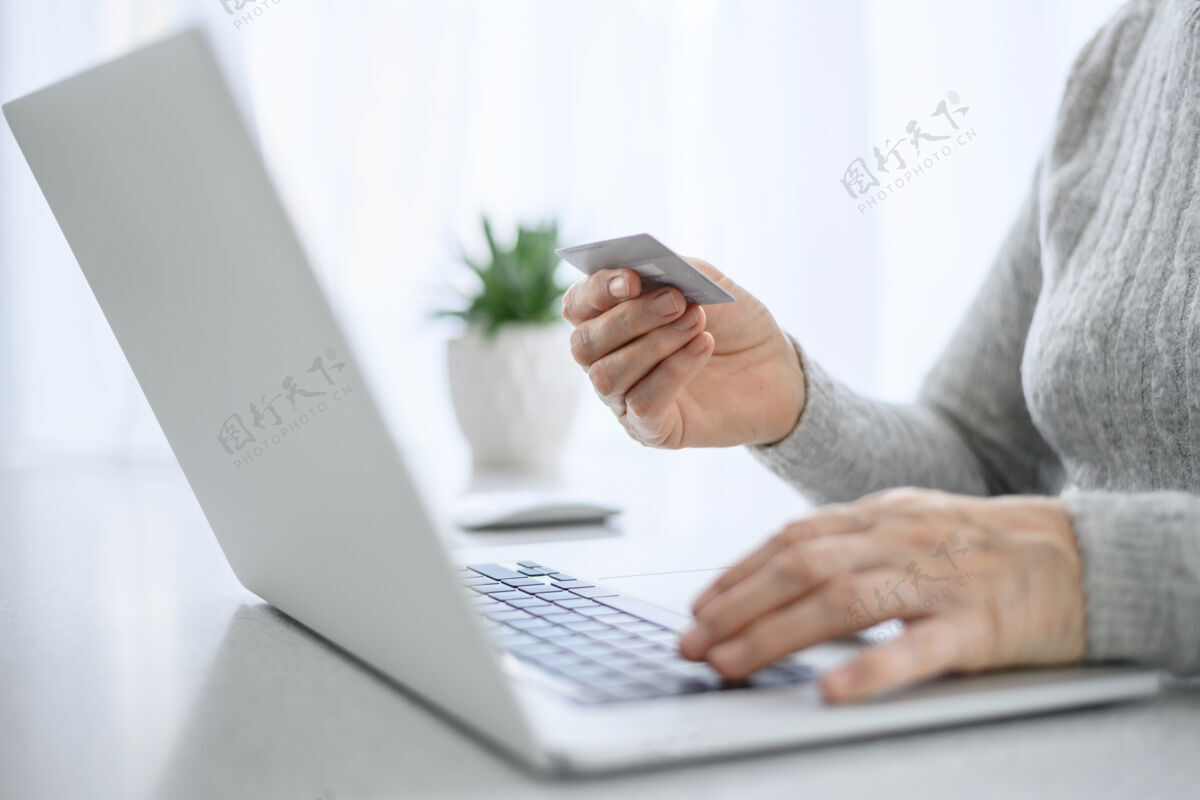 技术在日常生活中 一位女性高级职员的手在使用信用卡的笔记本电脑前工作工作成人个人电脑