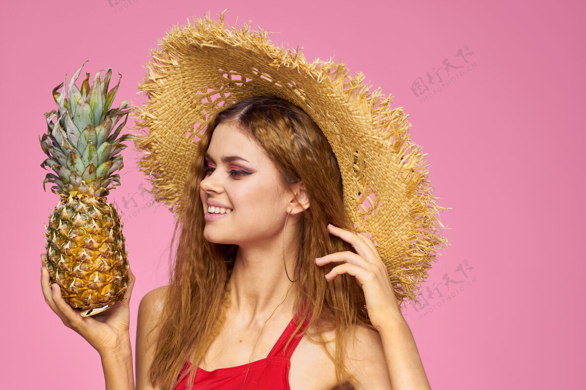 椰子女人手里拿着一顶带枪的草帽亮丽的妆容异国水果夏日粉红成人饮料魅力
