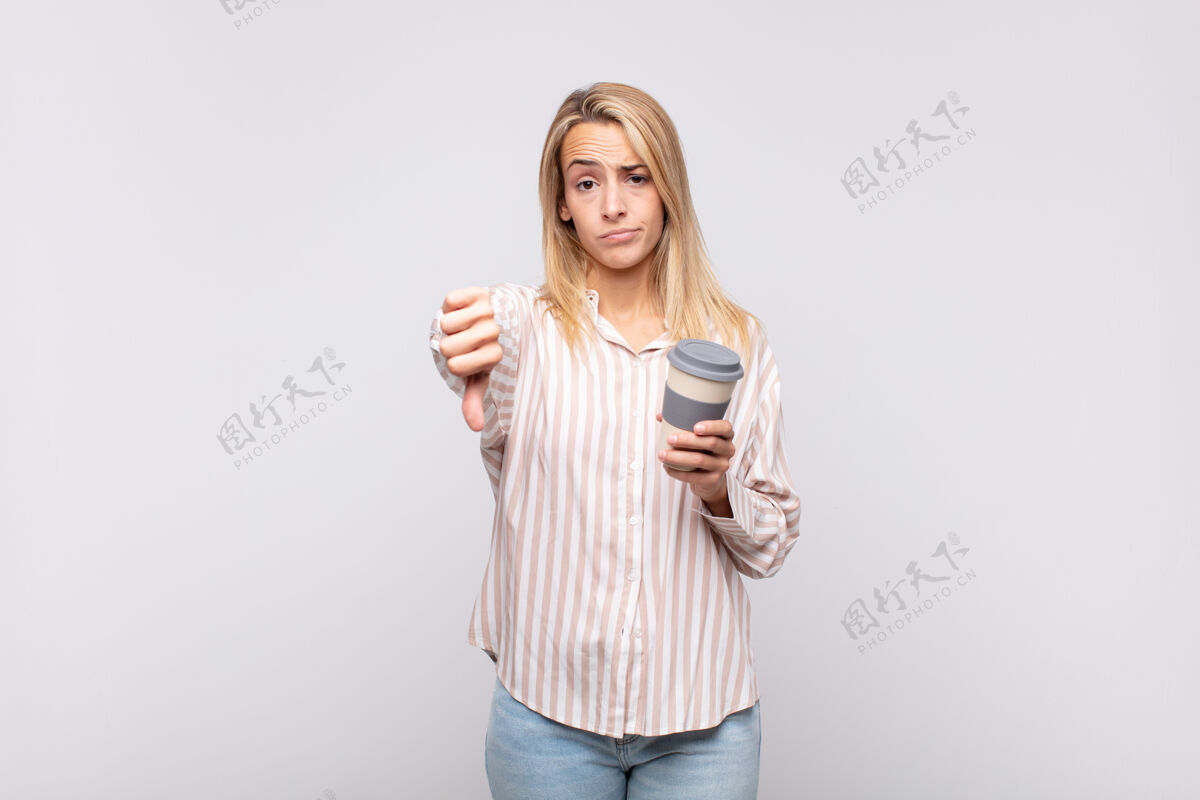 悲伤拿着咖啡的年轻女子生气 恼怒 失望或不高兴 严肃地竖起大拇指摩卡金发严重