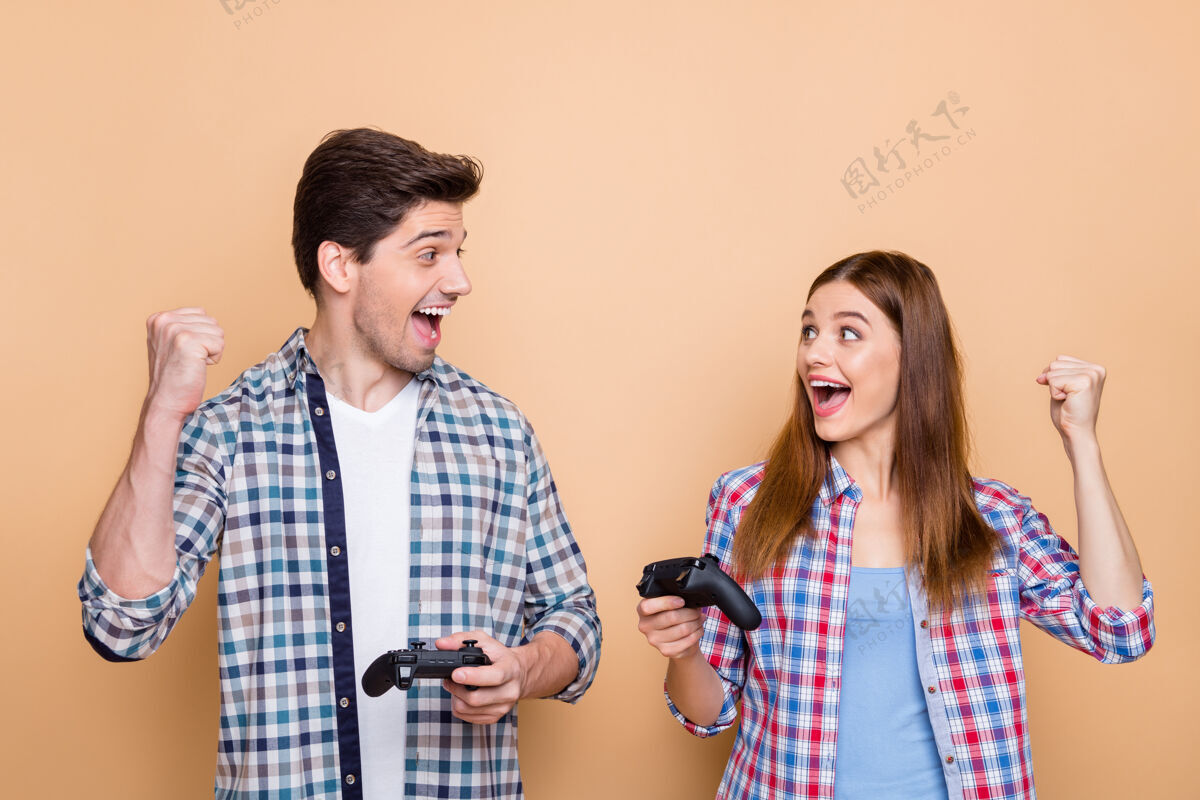 朋友照片中的白色欢快积极美丽时尚时尚的两个人玩游戏机与操纵杆赢得了比赛 在队孤立的米色粉彩背景情侣妻子丈夫