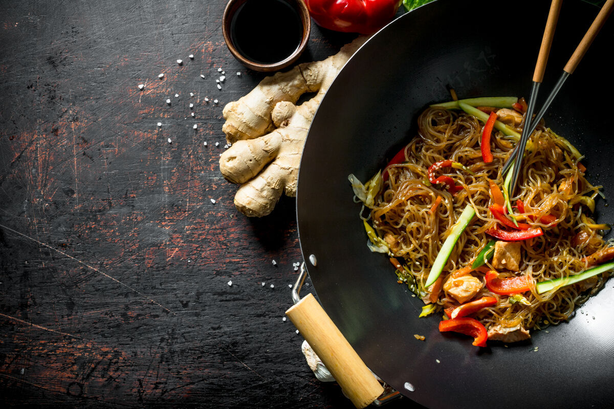 顶视图在深色的木桌上放着新鲜的中国面条 三文鱼 蔬菜和沙司蔬菜酱油洋葱