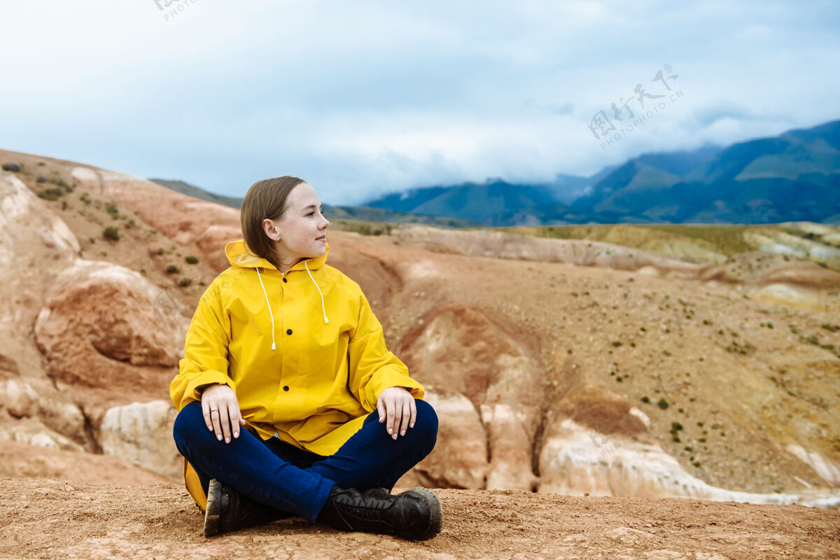 年轻坐在山上的徒步女孩户外坐着快乐
