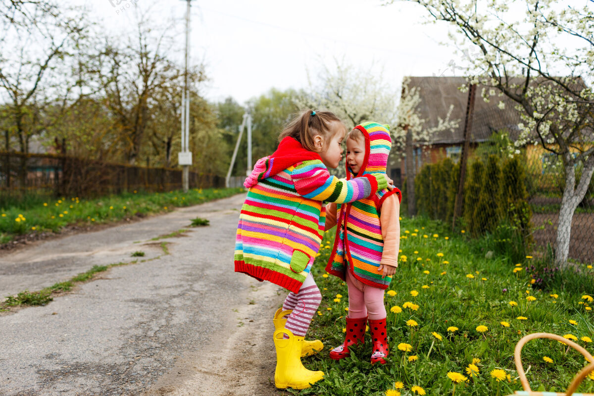 宝贝两个穿着鲜艳衣服的小女孩在黄色的树林里互相拥抱蒲公英快乐童年孩子小太阳