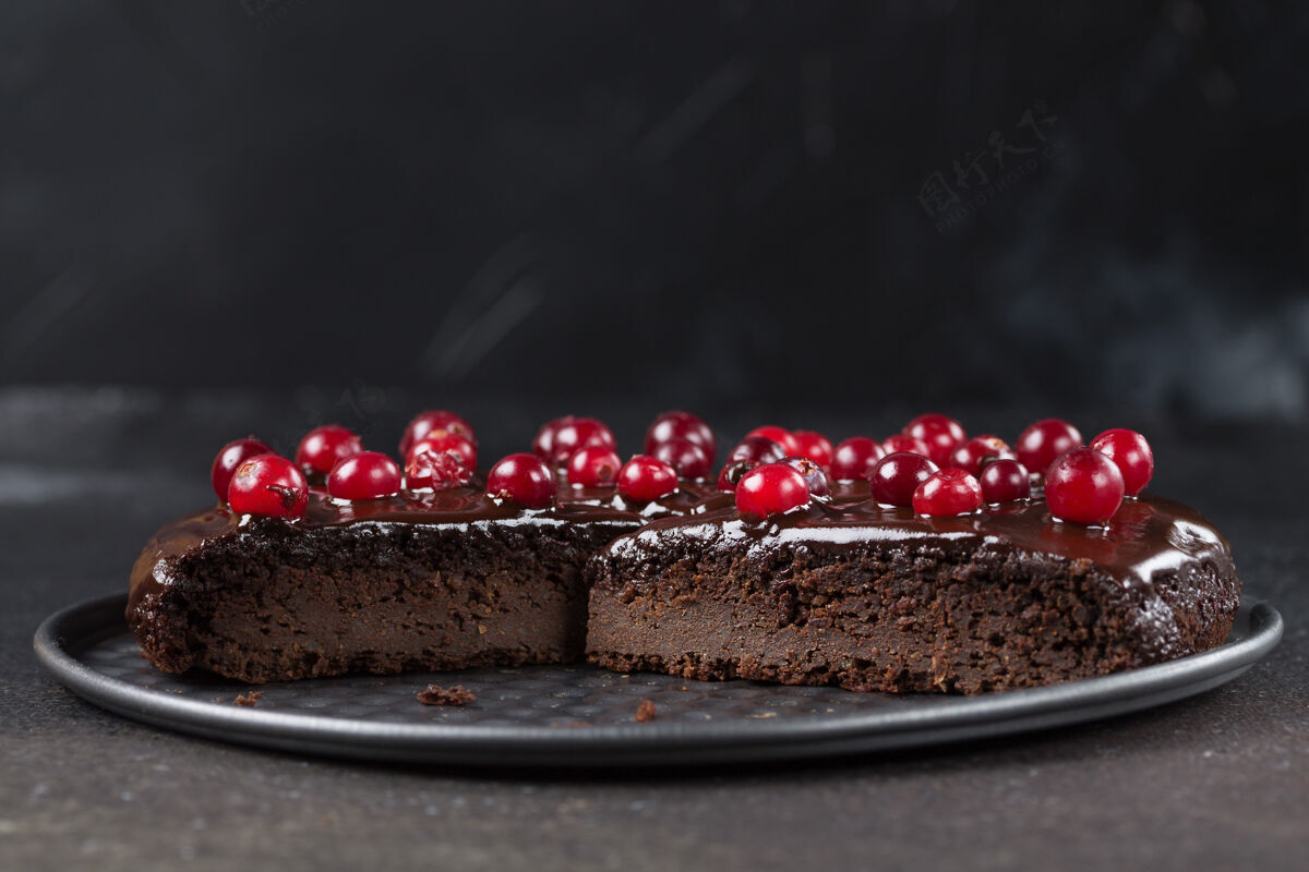 甜点一块没有麸质的巧克力蛋糕 用小红莓装饰 放在盘子里 放在黑色的盘子里背景.copy太空健康吃东西美食假日巧克力饼