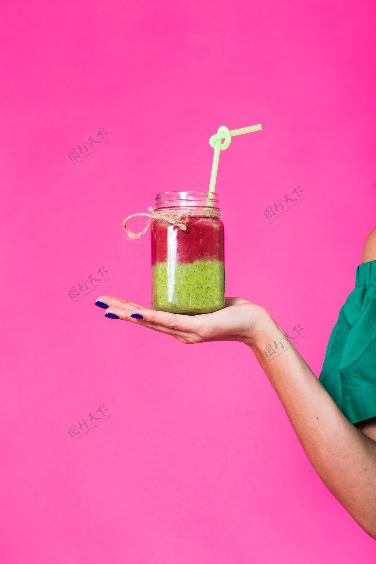 饮食粉红色墙上年轻女子手捧美味的绿色奶昔喝着的画像吸管别针年轻