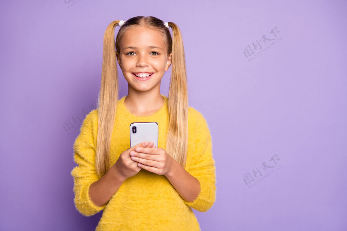 正面照片中的开朗积极可爱的女孩微笑着牙齿微笑 微笑着靠近空旷的空间孤立的紫罗兰色粉彩墙聊天浏览在线