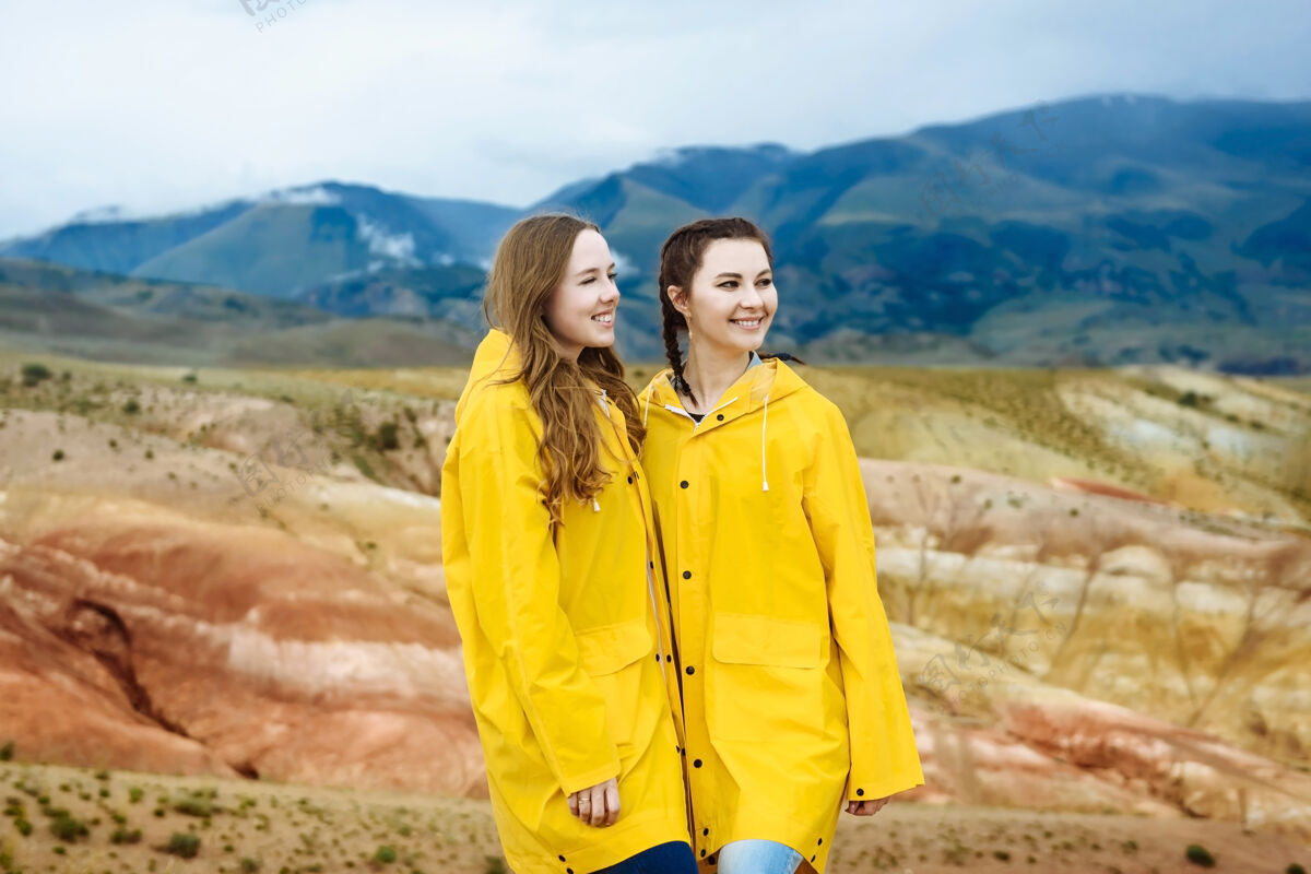快乐两个快乐的女游客在彩山的背景下山户外年轻